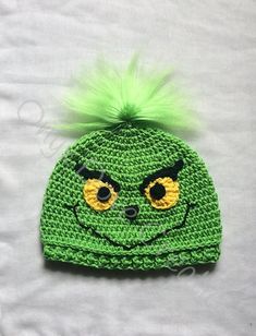 a crocheted hat with green hair and eyes