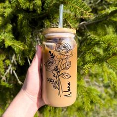 a hand holding a mason jar with flowers on it