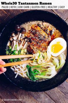 someone holding chopsticks over a bowl of ramen with vegetables and an egg