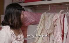 a woman is looking at some clothes hanging on a rack with words that read yeah, i love pink