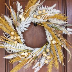 a wreath with white and yellow flowers is hanging on a door