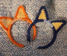 two crocheted cat ears laying on top of a blue and white cloth covered surface