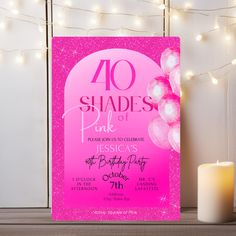 a pink birthday party poster with balloons and lights on the wall next to a lit candle