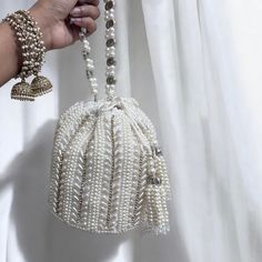 Introducing our exquisite Bridal Potli Bag in Ivory, a perfect accessory for your wedding day. Crafted from luxurious raw silk, this potli bag embodies elegance and sophistication. The delicate beadwork and sparkling crystal embellishments adorn the bag, adding a touch of opulence and grace. The bag features a stunning handmade handle, intricately embellished with beads and crystals, offering both beauty and functionality. Designed to complement your bridal attire, this potli bag is the ideal ch Reception Potli Bag With Pearl Embroidery, White Hand Embellished Clutch, White Hand Embellished Clutch Bag, Hand Embellished White Clutch Bag, Beige Hand Embellished Wedding Bag, Beige Hand Embellished Bag For Wedding, White Hand Embellished Party Bag, Hand Embellished Beige Bag For Wedding, Beige Pearl Embellished Evening Bag For Wedding