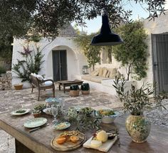 an outdoor table with plates and food on it in front of a house that's outside