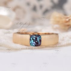 a gold ring with a blue topazte stone in the center on a white background