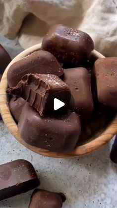 a wooden bowl filled with chocolate pieces on top of a table