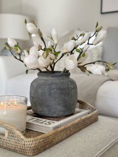 a vase with white flowers sitting on top of a tray next to a candle