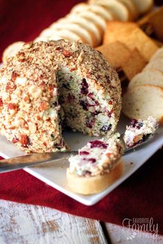 a white plate topped with a cheese ball covered in cranberry sauce next to crackers