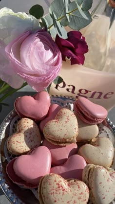 pink and white heart shaped macaroons in a bowl next to a purple rose