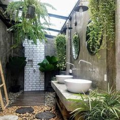 an outdoor bathroom with two sinks and mirrors on the wall, surrounded by greenery