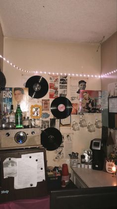 a room filled with lots of records on the wall and lights hanging above it,