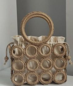 a handbag made out of woven material with circles and tassels on the handles