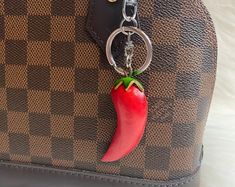 a brown and black purse with a red pepper on the front, attached to it