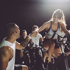 a group of people riding stationary bikes in a dark room with spotlights on the floor