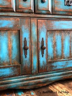 an old dresser is painted blue and has knobs on the doors, which are rusted