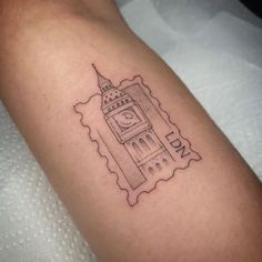 a black and white photo of a tattoo with a clock tower on it's arm