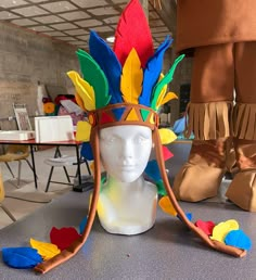 a headdress made out of paper with feathers on the top and bottom, sitting on a table