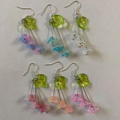 six pairs of earrings with different colored glass beads and dangling earwires on white background