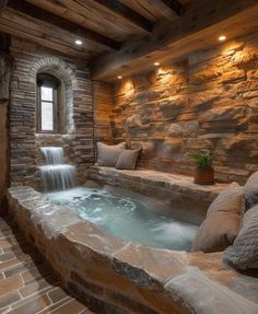 an indoor hot tub with water running down the side and pillows on the floor next to it