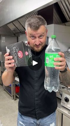 a man holding up a bottle of water in a kitchen