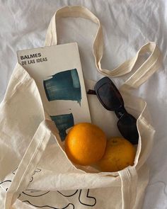 an orange and sunglasses in a bag on a bed