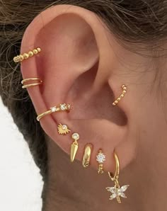 a woman wearing gold ear piercings with flowers and leaves