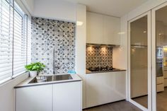 a kitchen with white cupboards and counter tops next to a window covered in blinds