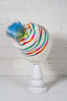 a white hat with multicolored stripes and a blue pom - pom