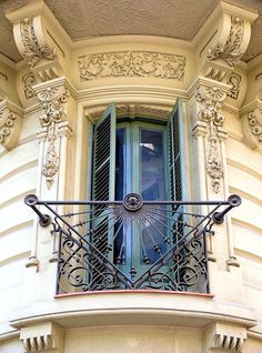 an ornate balcony with wrought iron balconies and window shutters on a building