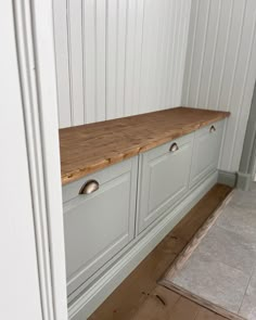 a kitchen with white cabinets and wood counter tops on the bottom shelf, next to a rug