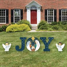 an outdoor yard decoration with the word joy surrounded by angel statues in front of a brick building