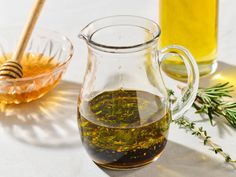 a glass pitcher filled with olive oil next to a bowl of honey