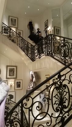 a woman is walking down the stairs in a house with pictures on the walls and below her