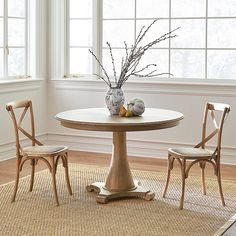 a table with two chairs and a vase filled with flowers sitting on top of it