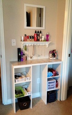 a white shelf filled with lots of bottles next to a mirror and other items on top of it