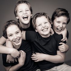 a group of young boys hugging each other with their arms around one another and smiling at the camera