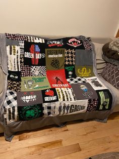 a couch covered in patches and stickers sitting on top of a hard wood floor