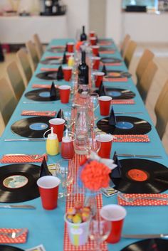 a long table set up for a party with vinyl records on the table and red cups