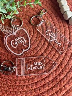 two clear acrylic key chains sitting on top of a red mat next to a green plant