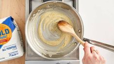 a person stirring something in a pan with a wooden spoon