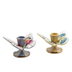 two teacups with saucers on them sitting side by side, one is gold and the other has floral designs