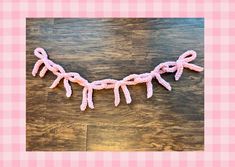 a crocheted pink ribbon is hanging on a wooden table