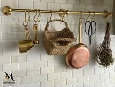 several pots and pans are hanging on the wall with gold hooks in front of them