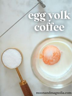 an egg yolk in a glass bowl next to a whisk and spoon