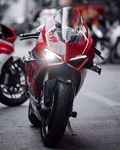 a red motorcycle parked on the street next to other motorcyclist's