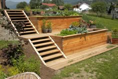 an outdoor garden area with wooden steps and raised planter boxes on the side of it