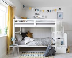 a white bunk bed sitting in a bedroom next to a yellow curtained window and rug