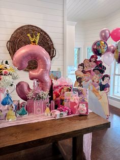 a table topped with lots of pink balloons and princess themed items on top of it