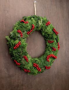 a green wreath with red berries hanging on a wall